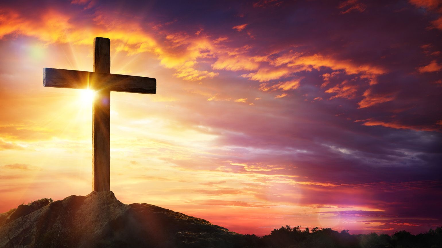 Christian cross at sunset with light and clouds; Getty Images