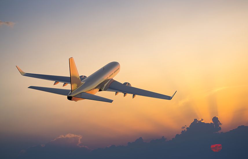 Airplane flying above clouds at sunset