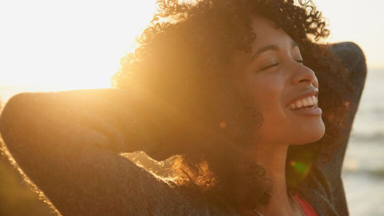 A woman smiles at sunrise