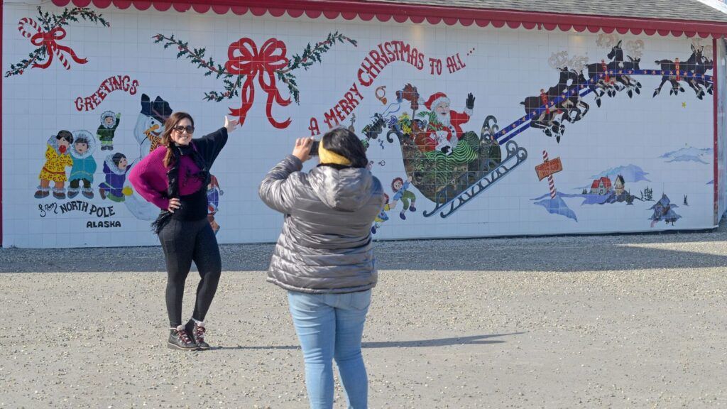 A tourist poses for a photo in front of a painted wall in the real North Pole