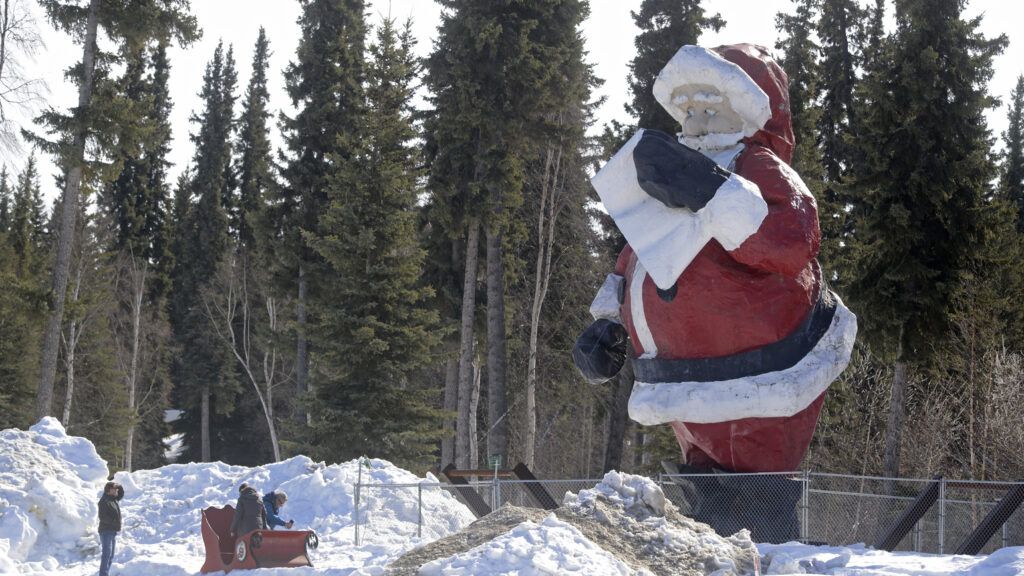 People stand in front of the giant Santa statue outside of Santa Claus House