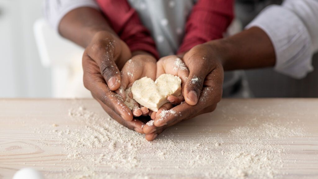 Father and son's hands making a heart shaped cookie to signify God's love