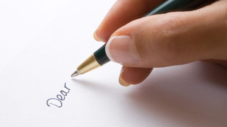 A close-up of a woman's hand writing a letter; Getty Images