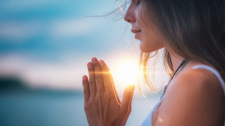 A woman prays at sunrise; Getty Image