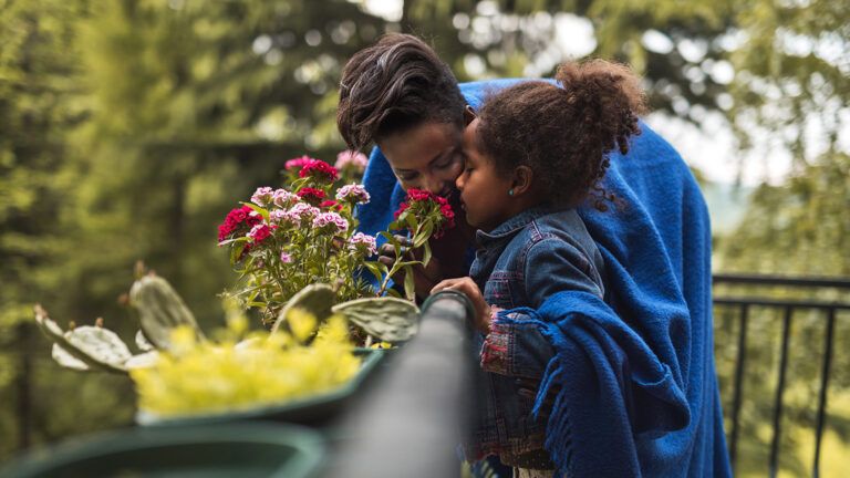 A mother and daughter smelling spring flowers